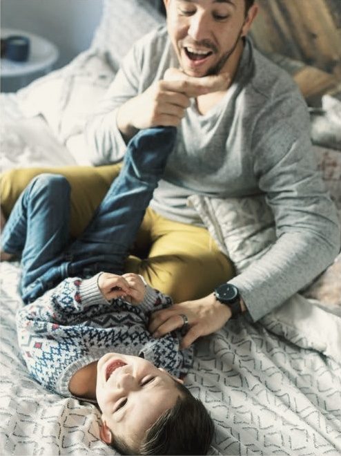 Dad tickling his son on the bed