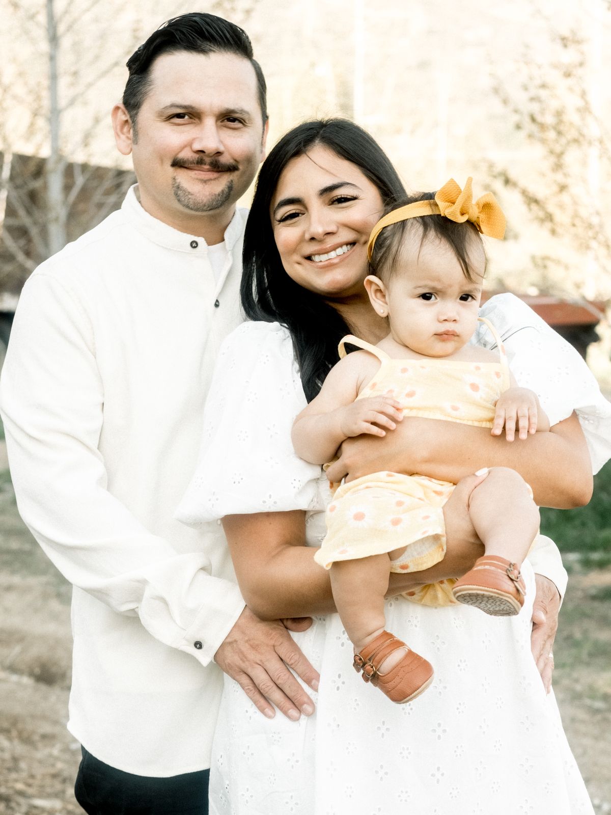 Parents holding their baby daughter in a yellow dress