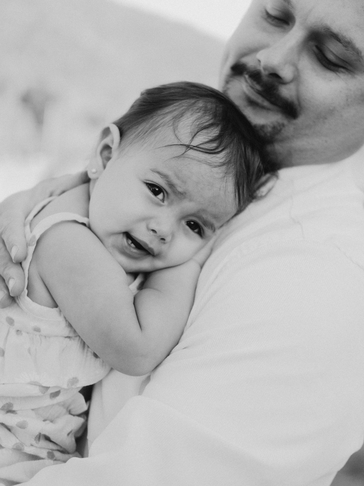 Black and white photo of a father holding his baby against his cheek