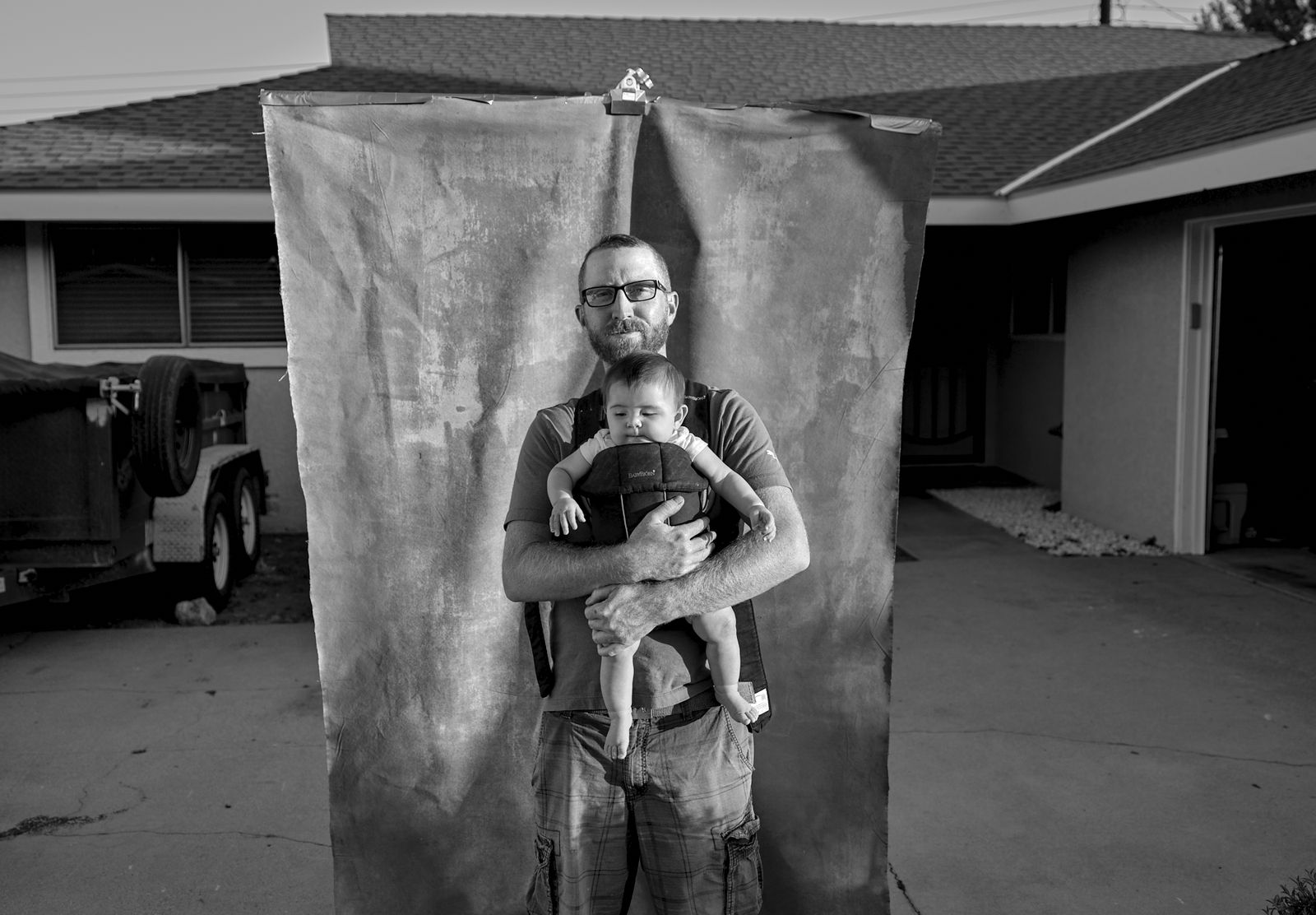 A father holding his newborn in front of a hand-held backdrop