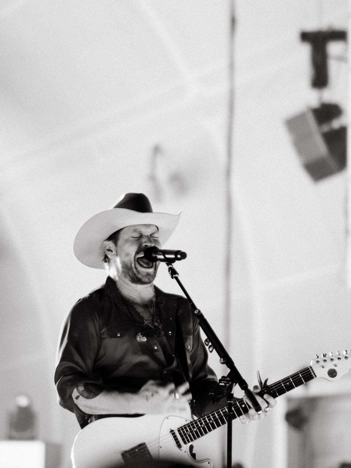 Black and white photo of a singer in a cowboy hat playing guitar on stage