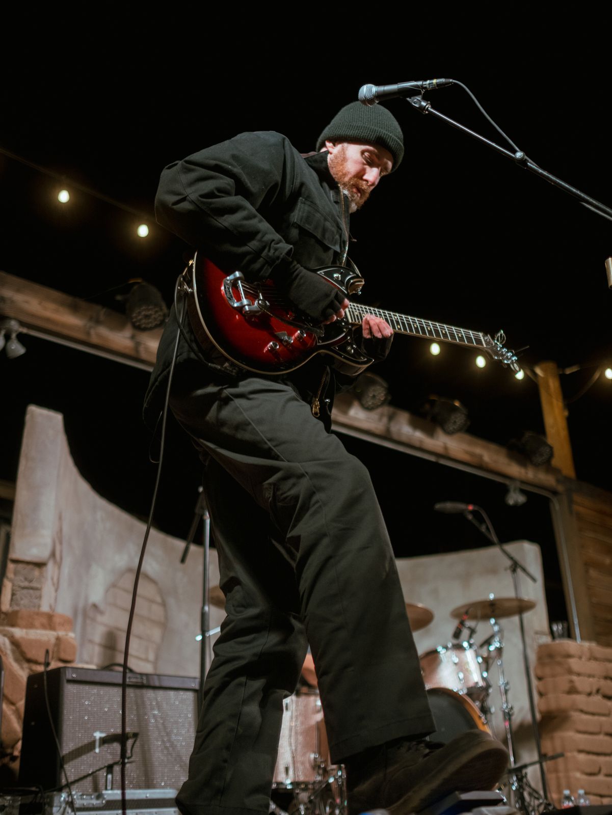 Black and white photo of a guitarist mid-leap on stage
