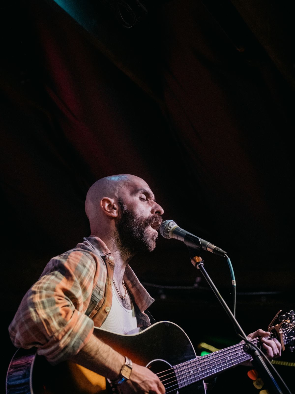 A singer with an acoustic guitar under warm stage light