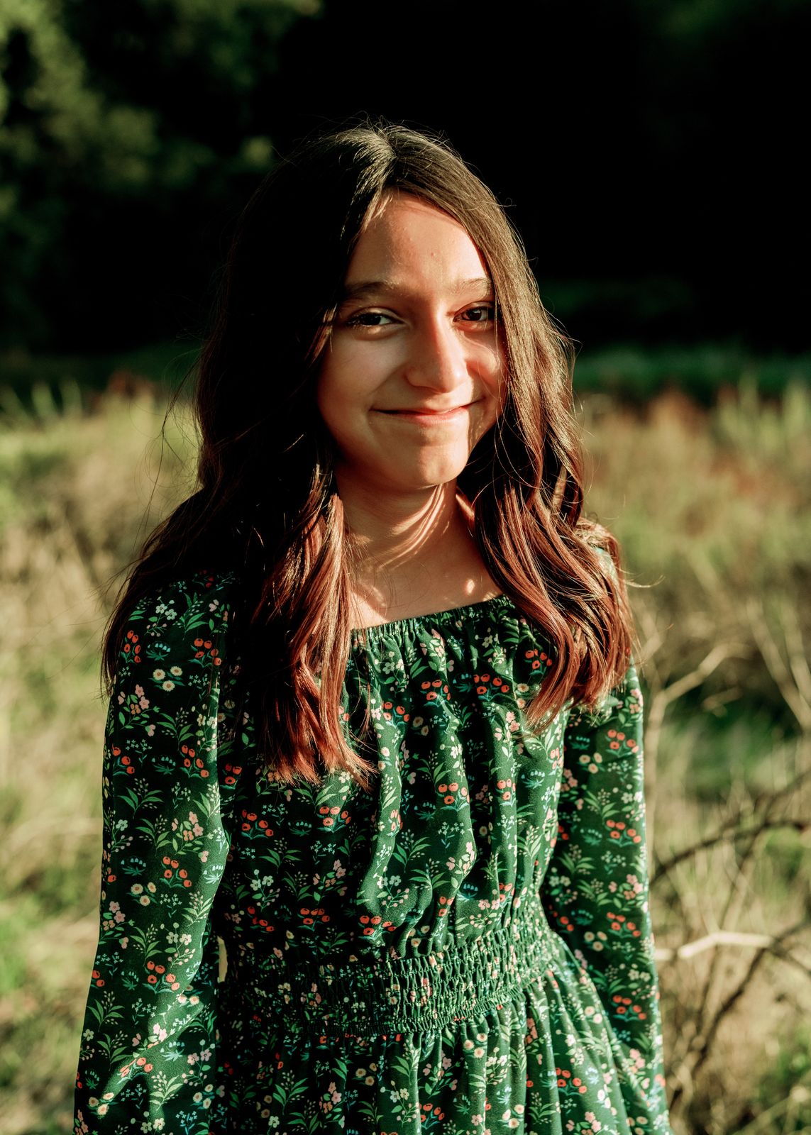 A girl in a green dress smiling in golden light