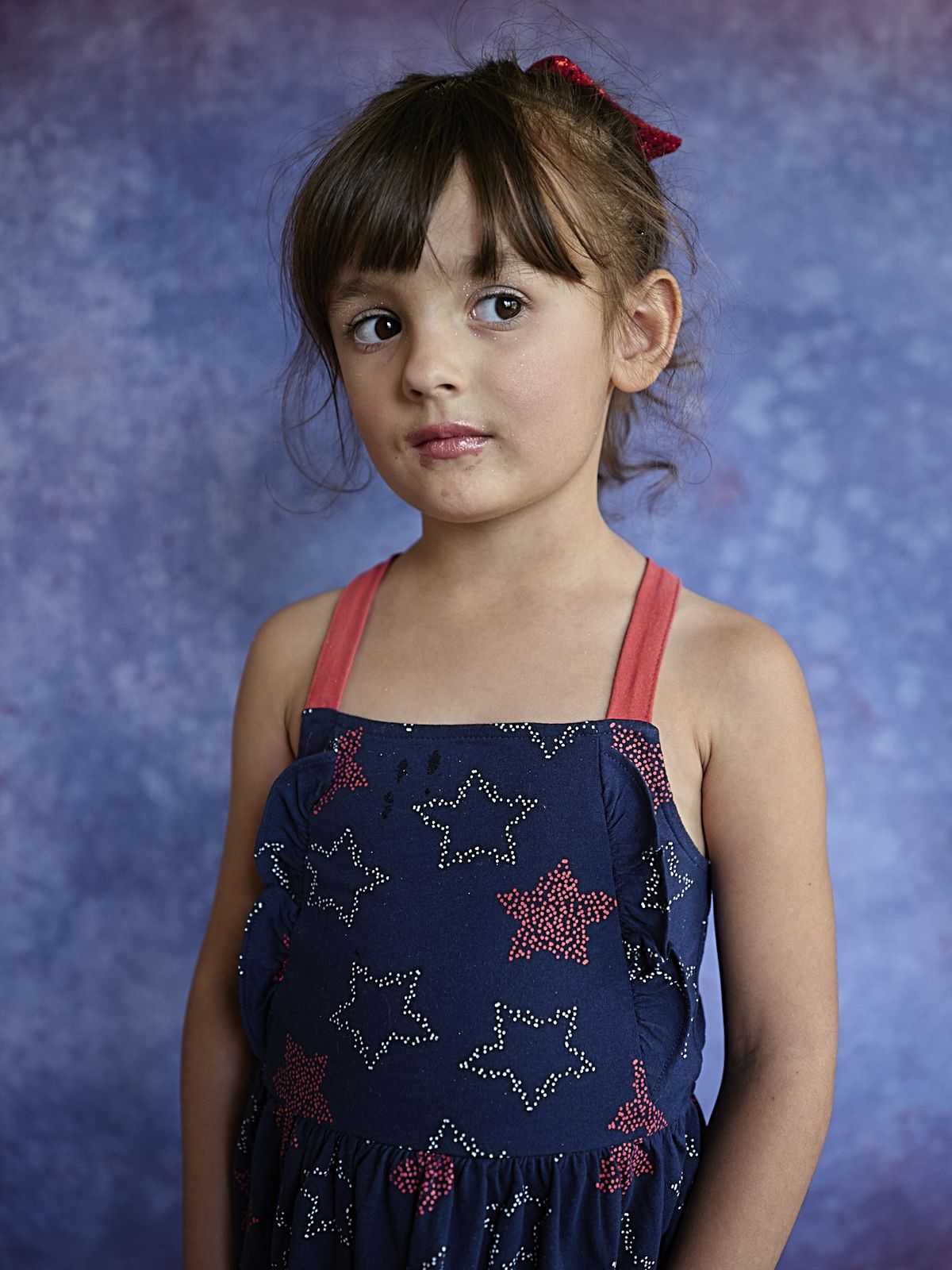 A young girl in a starred dress against a painted backdrop