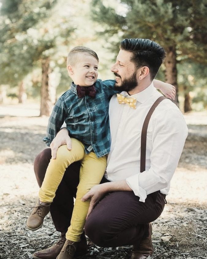 Dad holding his son on his knee in a pine grove