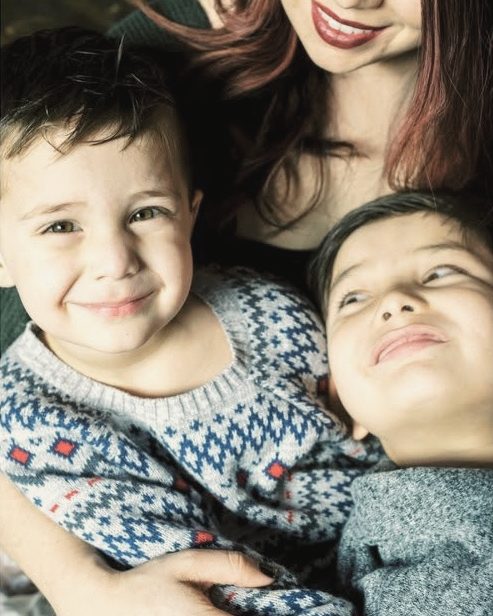 Two young brothers smiling next to their mom