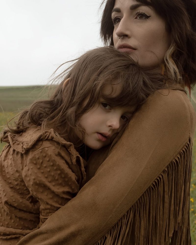 Mom hugging her daughter in a field
